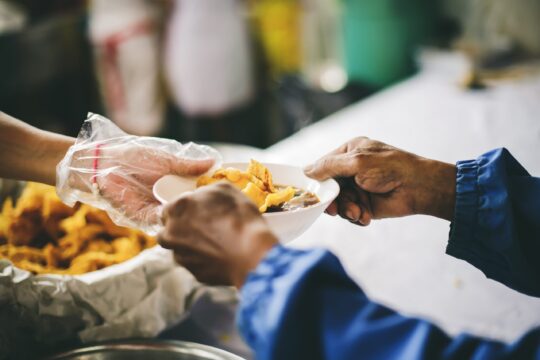 Volunteers scooping the food to share with the needy : concept of providing free food to homeless people.